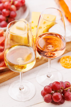 A delectable arrangement of various cheeses, fresh grapes, prosciutto and wine, creating an elegant display for a gourmet dining experience. Perfect for wine and cheese loversの写真素材