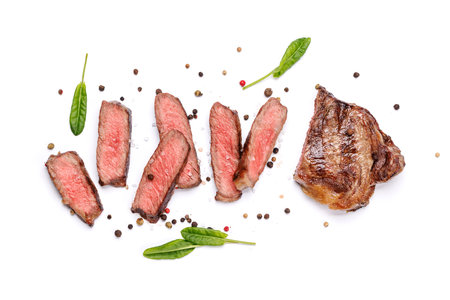 A perfectly cooked sliced striploin steak with a juicy, tender texture isolated on a white background. A gourmet meal for steak and wine loversの写真素材
