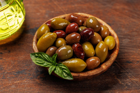 An assortment of various olives presented in a bowl, showing different colors, textures, and flavorsの写真素材