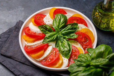 A vibrant and appetizing display of Caprese antipasti featuring slices of ripe garden tomatoes, fresh mozzarella, and aromatic basil leavesの写真素材