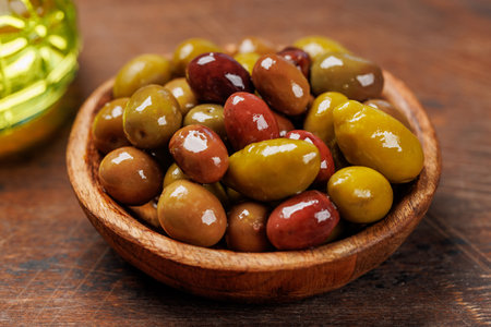An assortment of various olives presented in a bowl, showing different colors, textures, and flavorsの写真素材