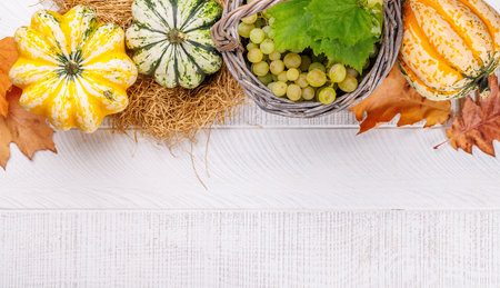 Autumn-themed food arrangement with pumpkins, pears, grapes, and autumn leaves on a table, creating a cozy seasonal atmosphere. Includes copy space for your contentの写真素材