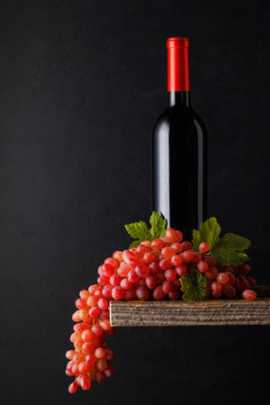 A bottle of wine paired with grapes, set against a dark background, creating a rich and elegant ambianceの写真素材