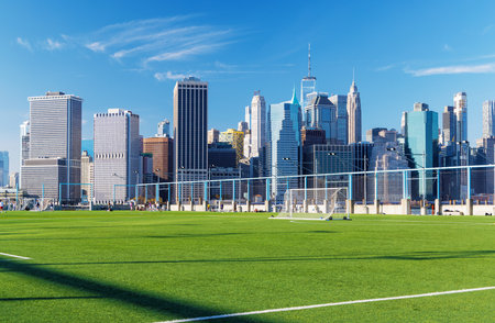 A football field on Brooklyn's pier with the Manhattan skyscrapers towering in the background, showcasing an urban landscape blend of sport and city viewsの写真素材