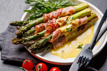 Grilled asparagus with bacon and egg sauce on a plateの写真素材