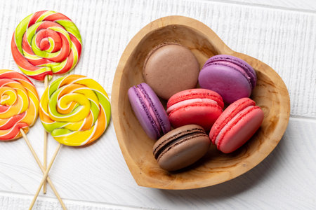 Various colorful candies, lollipops, and macaroons. Flat lay over wooden backgroundの写真素材