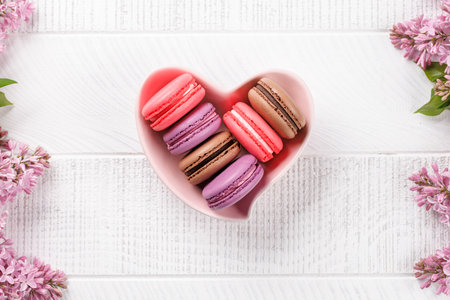 Colorful macaroons in heart shaped bowl, arranged in a delightful display of vibrant hues and irresistible sweetnessの写真素材