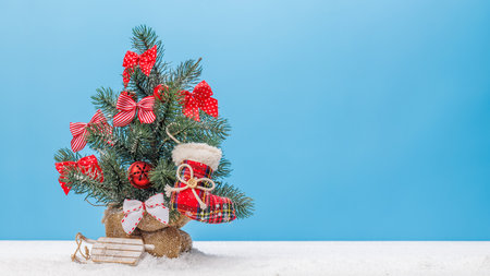 Cozy winter charm: Small decorated snowy Christmas tree with copy spaceの写真素材