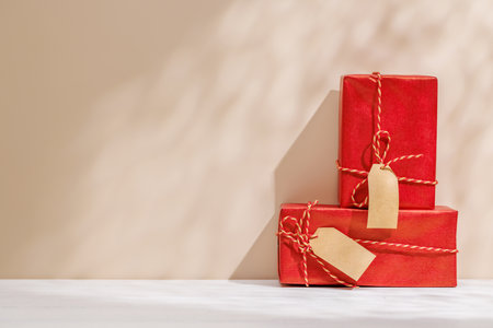 Christmas template featuring gift boxes on a table with shadows and sun glares softly falling on the wall, creating a festive winter atmosphereの写真素材