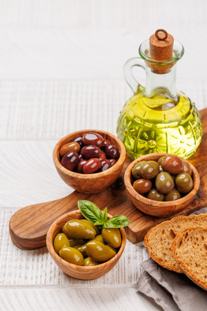 An assortment of various olives presented in a bowl and olive oil bottle, showing different colors, textures, and flavors. With copy spaceの写真素材