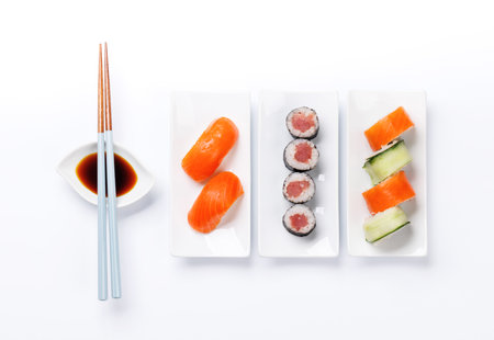 Assorted sushi and maki rolls beautifully arranged on plates, featuring fresh ingredients and vibrant colors, on a clean white backgroundの写真素材