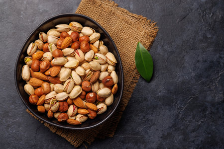 A vibrant mix of various nuts, including almonds, walnuts, hazelnuts, cashews, and pistachios, displayed in an appetizing arrangement, perfect for healthy snacking or culinary inspirationの写真素材