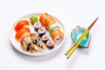 Assorted sushi and maki rolls beautifully arranged on plate, featuring fresh ingredients and vibrant colors, on a clean white backgroundの写真素材