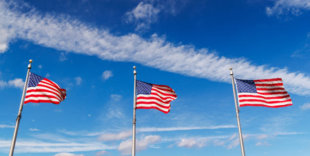 Rows of American flags waving against a sunny sky, showcasing patriotic pride with vivid colorsの写真素材