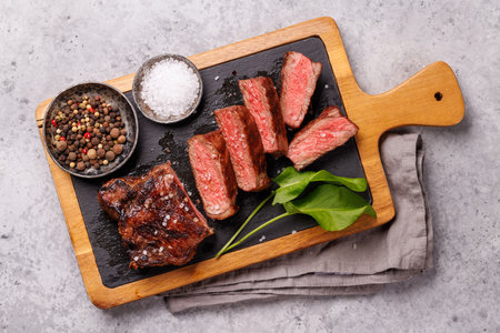 A perfectly cooked sliced striploin steak with a juicy, tender texture on a dark background. A gourmet meal for steak and wine loversの写真素材