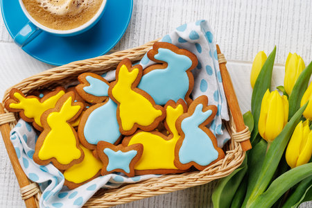 Easter Scene with Bunny-Shaped Gingerbread Cookies, Yellow Tulips, and Coffee Cupの写真素材