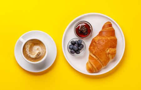 Flaky golden croissant served with fresh blueberries and a side of sweet berry jam for a delightful breakfast or snackの写真素材