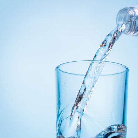 Crystal clear water being poured into a transparent glass with ice, creating refreshing ripples and bubbles. A perfect representation of hydration and purityの写真素材