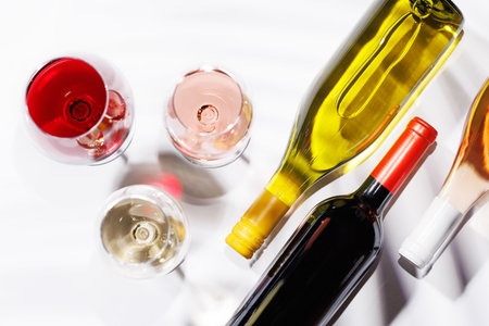 Three wine glasses filled with red, white, and rose wine, standing gracefully on a bright, minimalist background. A vibrant display of wine's variety and eleganceの写真素材