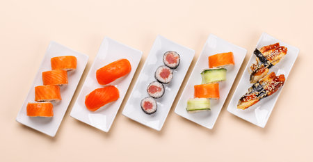 Assorted sushi and maki rolls beautifully arranged on plates, featuring fresh ingredients and vibrant colors, flat lay on a clean beige backgroundの写真素材