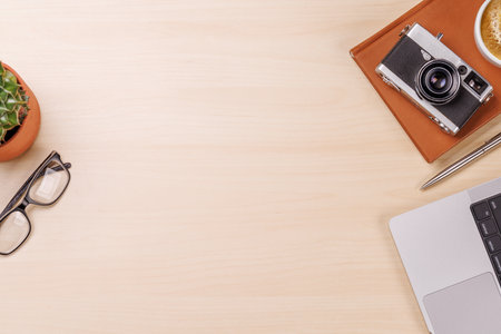A clean and minimal desk setup featuring a laptop, camera and a coffee cup, providing a perfect workspace with ample copy space for design or textの写真素材