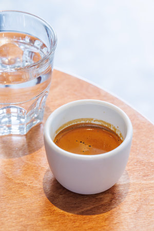 Freshly brewed espresso served in a small cup on a table, capturing the rich aroma and bold flavor...