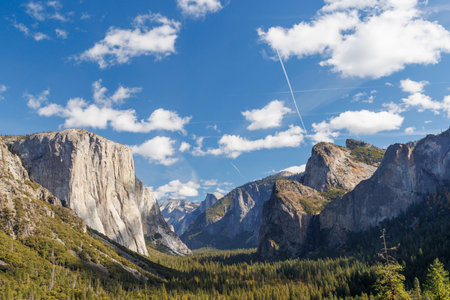 The breathtaking Tunnel View in Yosemite National Park showcases a panoramic vista of El Capitan, Half Dome, and Bridalveil Fall, surrounded by towering granite cliffs and lush forestsの写真素材