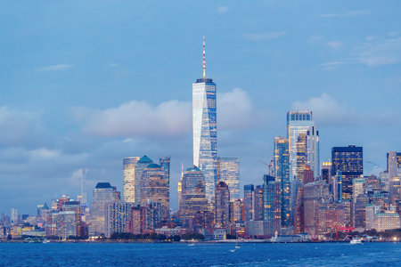 A vibrant sunset panorama of Manhattan downtown skyline, viewed from the river, with skyscrapers illuminated by warm, golden huesの写真素材