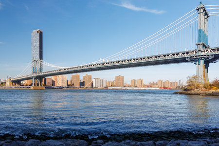 Iconic view of Manhattan Bridge with Manhattan skyscrapers in the background, captured from Dumbo, showcasing urban elegance under a radiant skyの写真素材