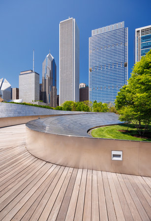 Sunny view of downtown Chicago with iconic skyscrapers rising above Millennium park in the foreground, showcasing the city's vibrant blend of nature and architectureの写真素材