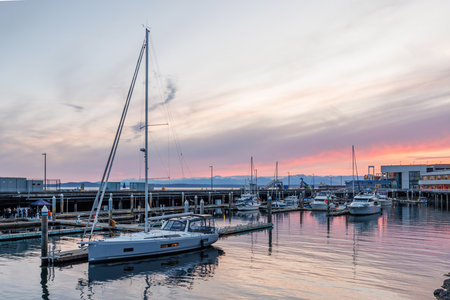 Seattle harbor during sunset with glowing sky, calm water, and silhouettes of boatsの写真素材