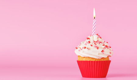 Festive cupcake topped with swirled frosting and a lit candle. Perfect for birthday celebrations or special occasions with copy spaceの写真素材