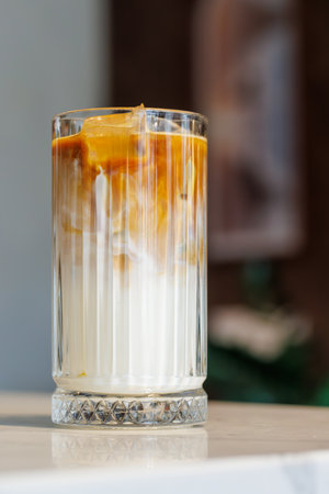 Iced latte in a clear glass with visible coffee and milk layers on a sunny dayの写真素材