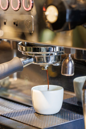 Espresso machine brewing fresh coffee into a cup with rich crema forming on topの写真素材