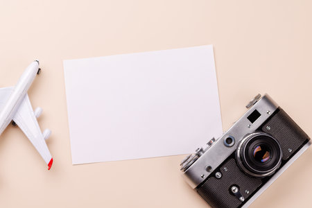Travel-themed flat lay with blank photo card, camera, toy airplane, arranged creatively on table with copy space for your ideasの写真素材