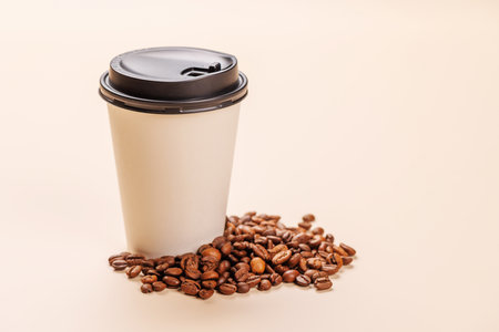 A paper cup of freshly brewed coffee surrounded by rich, aromatic roasted coffee beans. A perfect representation of warmth, energy, and the love for caffeineの写真素材