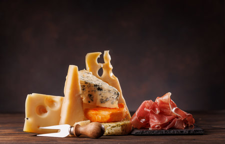 Assorted cheeses in different shapes and textures displayed together on a rustic surfaceの写真素材