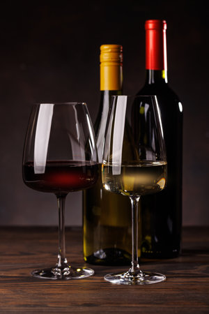 Wine glasses filled with wine beside a bottles on a wooden surface, creating an elegant and simple sceneの写真素材