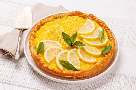 Delicious lemon tart with golden crust and smooth, glossy lemon filling, garnished lightlyの写真素材