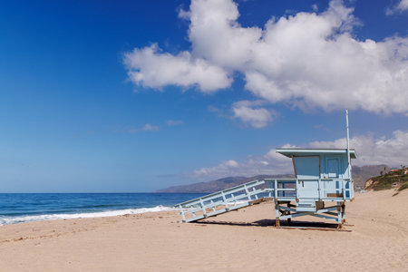 Lifeguard tower on a California ocean beach with golden sand and waves under a sunny skyの写真素材