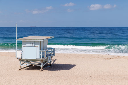 Lifeguard tower on a California ocean beach with golden sand and waves under a sunny skyの写真素材