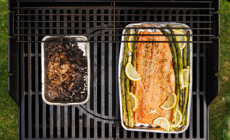 Grilled salmon fillets and asparagus sizzling on a barbecue grill with smoky char marksの写真素材