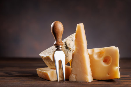 Assorted cheeses in different shapes and textures displayed together on a rustic surfaceの写真素材