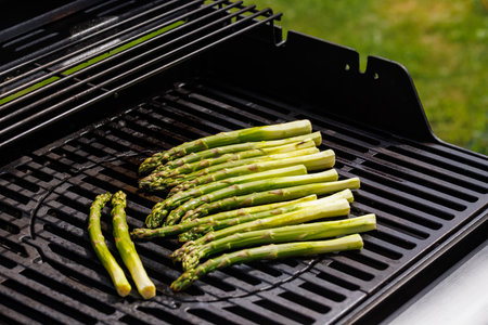 Fresh asparagus spears sizzling on a hot grill with char marks and smoky aroma risingの写真素材