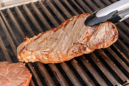 Juicy steak on a grill with flames and smoke risingの写真素材