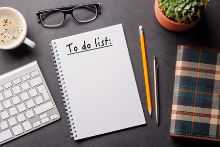 Organized work desk setup with PC, office supplies, coffee and a notepad for writing a to-do list. Top view with clean, productive layoutの写真素材