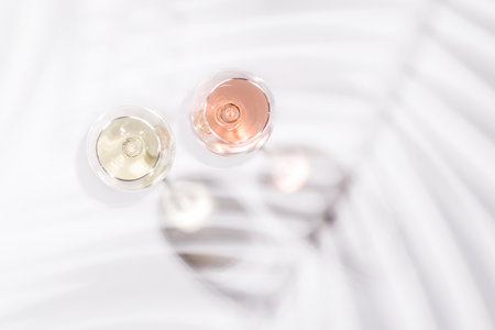 Two wine glasses filled with rose and white wine, standing gracefully on a bright, minimalist background. A vibrant display of wine's variety and eleganceの写真素材