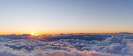 Sunset above the clouds with warm colors and soft light filling the skyの写真素材
