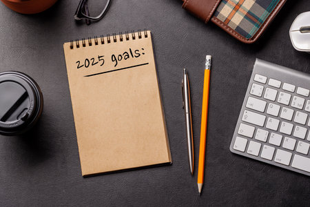 Elegant leather desk setup with laptop, coffee, stationery, and a notepad labeled 2025 Goals. A sleek workspace for planning and productivityの写真素材