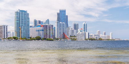 Modern skyline of Miami with towering skyscrapers, tropical vibe, and waterfront views under a sunny...